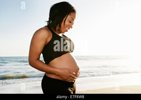 Pregnant woman holding her belly on beach Banque D'Images