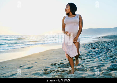 Pregnant woman holding her belly on beach Banque D'Images