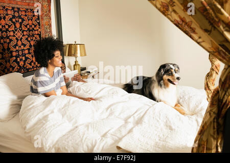 Mixed Race woman with dog in bed Banque D'Images