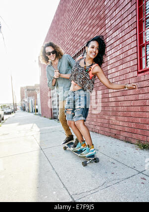 Couple riding skateboard on city street Banque D'Images