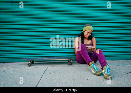 Hispanic woman using cell phone on city street Banque D'Images