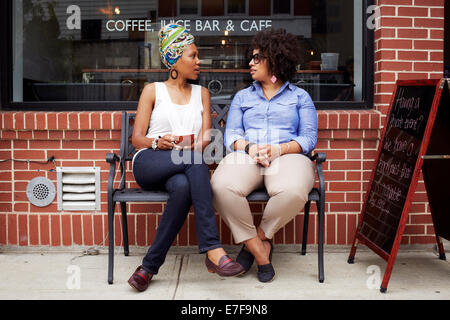 Des femmes qui parlent en dehors de coffee shop on city street Banque D'Images