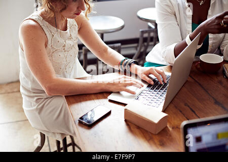 Woman using laptop in cafe Banque D'Images