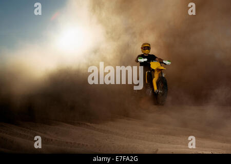 Caucasian man riding dirt bike dans un nuage de poussière Banque D'Images