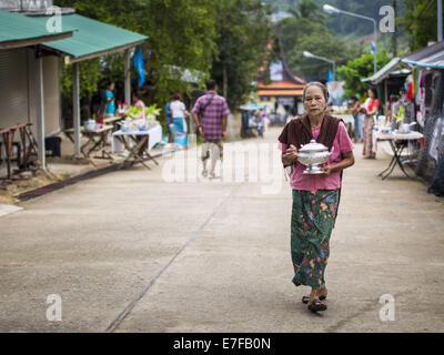 Sangkhla Buri, Kanchanaburi, Thaïlande. 16 Sep, 2014. Une femme marche sur la route pour faire mon présent et mérite des moines bouddhistes avec des aliments durant la matinée l'aumône ronde de la communauté dans Mon Sangkhla Buri. Les LUN sont certaines des premières personnes à s'installer dans le sud-est asiatique, et étaient responsables de la propagation du Bouddhisme Theravada en Thaïlande et en Indochine. La Mon pays est dans le sud-ouest de la Thaïlande et le sud-est du Myanmar (Birmanie). Credit : ZUMA Press, Inc./Alamy Live News Banque D'Images