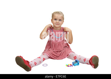 Cute little girl sits et essayer les bijoux. Portrait isolé sur fond blanc Banque D'Images