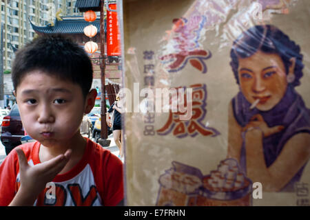 Un enfant marche près d'une annonce dans l'ancienne ville, Shanghai, Chine. La vieille ville de Shanghai, Shànghăi Lăo Chéngxiāng, als Banque D'Images