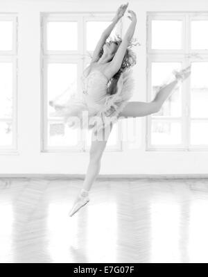 Jeune, belle ballerine exerçant en studio. Une image en noir et blanc avec du grain ajouté comme effet. Banque D'Images