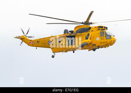 RAF jaune vif avec deux hélicoptères de sauvetage permanent de l'équipage en porte ouverte en vol au dessus de Whitby, Angleterre Banque D'Images