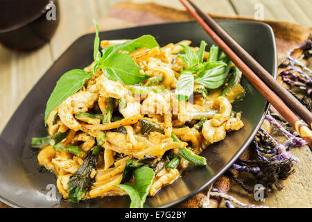 Sauté de poulet avec l'oignon, l'ail, la pâte de cari, long bean, pousses de bambou, et le lait de coco, servi avec le basilic thaï Banque D'Images