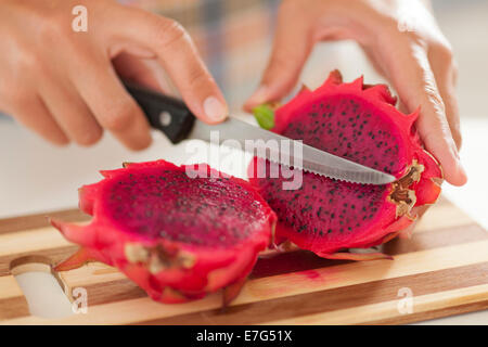 Coupe femme fruit du dragon sur une planche à découper dans la cuisine. Banque D'Images