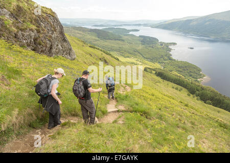 Trois marcheurs de colline en ordre décroissant Ben Lomond avec vue sur le Loch Lomond dans la distance Banque D'Images