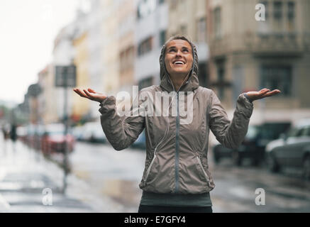 Remise en forme heureuse jeune femme capture de gouttes de pluie dans la ville Banque D'Images