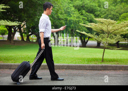 Businessman walking et à l'aide d'un téléphone sur la route Banque D'Images