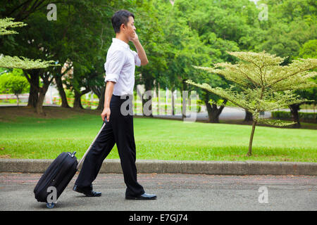 Businessman walking et à l'aide d'un téléphone sur la route Banque D'Images