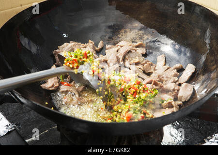 La cuisson au wok sauté (boeuf, piment, basilic) : l'alimentation, de l'alimentation de rue dans un marché à l'heure du déjeuner à Canary Wharf, London, UK Banque D'Images