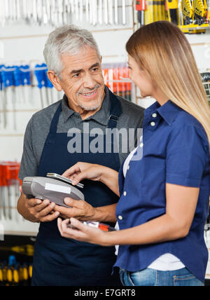 Femme de vos paiements sur mobilephone in hardware store Banque D'Images