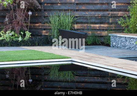 Petit bassin de jardin avec bassin de piscine sombre réfléchissant avec pavés de basalte muraux de bois de séquoia calciné carbonisé dans la cage de gabion Royaume-Uni Banque D'Images