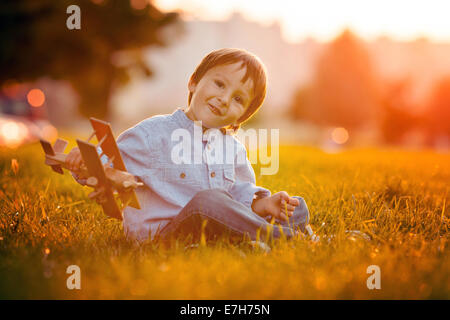 Cute boy, jouant avec avion sur le coucher du soleil dans le parc, smiling Banque D'Images