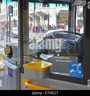 London bus driver au travail la conduite à droite à l'intérieur de la cabine du volant avec Oyster card reader et pictogramme audience England UK Banque D'Images