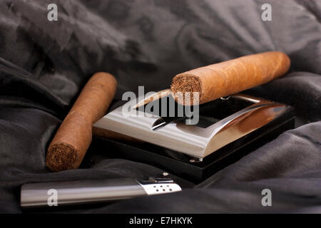 Close up of metallic cendrier, briquet et cigare cubain sur fond de soie noire Banque D'Images