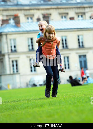 Enfants heureux, fille de l'école et son petit frère, jouant dans le parc de la ville, tournant ensemble de ferroutage Banque D'Images