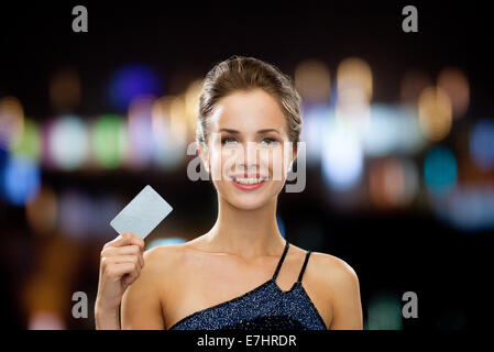 Smiling woman in evening dress holding credit card Banque D'Images