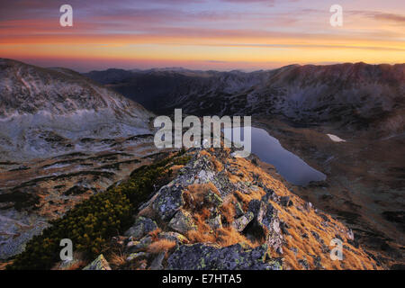 Magnifique coucher de soleil sur le lac Bucura - au milieu des hautes montagnes du Parc National Retezat, Roumanie. Banque D'Images