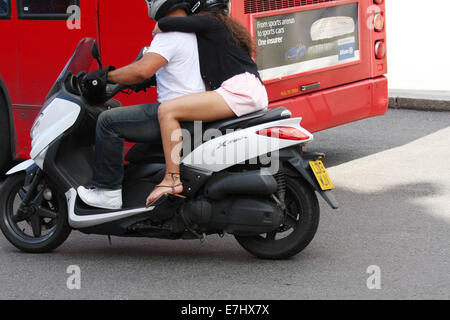 Un homme et de la femme un scooter à côté d'un bus à Londres Banque D'Images