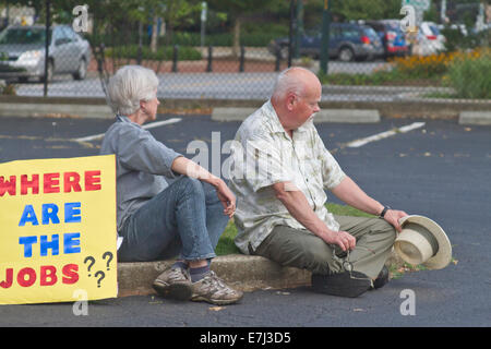 Couple est assis sur un trottoir après une morale lundi rallye avec un signe de demander "Où sont les emplois ?' Banque D'Images