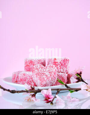 Style australien fait maison en forme de coeur rose petits gâteaux lamington avec fleur de printemps avec l'exemplaire de l'espace. Banque D'Images