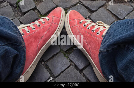 Pieds en rouge sneakers et jeans à l'extérieur. La première étape. Banque D'Images