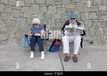 Un couple de retraités s'asseoir par une digue à Falmouth, Cornwall, UK Banque D'Images