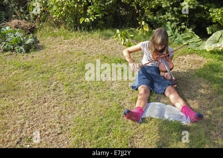 Une jeune fille de 11 ans son violon pratiques dans le jardin Banque D'Images