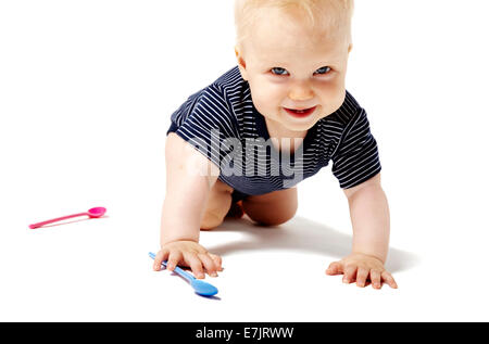 Happy baby girl de ramper sur les genoux et en regardant la caméra. Banque D'Images