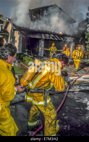 Un pompier de l'air changements son collègue réservoir masque pendant la lutte contre l'incendie accueil à Dana Point, CA. Banque D'Images