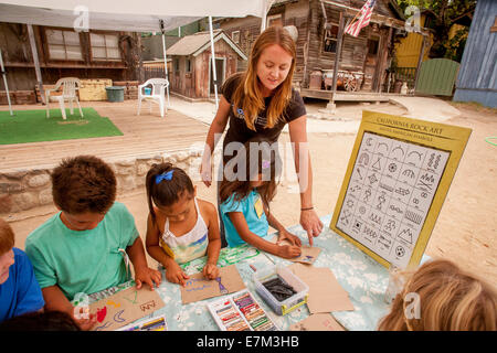 Un conservateur de musée d'anthropologie montre un groupe de jeunes des exemples de symboles de l'art rupestre amérindien alors que des conférences sur l'histoire de la tribu indienne Juaneno à San Juan Capistrano, CA. Les enfants sont symboles de dessin de leur propre conception. Banque D'Images