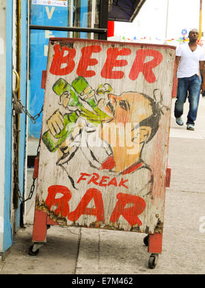 Un panneau publicitaire pour un bar est sur l'affichage sur un trottoir dans Coney Island, New York City. Remarque African American piéton. Banque D'Images