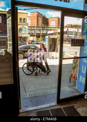 Vu à travers la porte de son attraction, un concessionnaire handicapés et son employé parler sur le trottoir dans Coney Island, New York. Remarque de métro et d'appartements dans ce fameux parc d'attractions. Banque D'Images