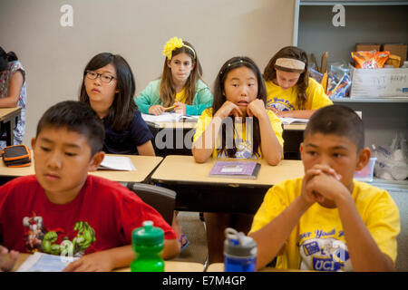 Asiatiques, Hispaniques et Caucasian middle school les élèves écoutent leur professeur à un atelier d'écriture de l'été à Irvine, CA. Remarque T shirts jaune. Banque D'Images