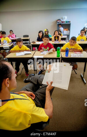 Les élèves de collège multiethnique comme écouter un enseignant lit 'les voyages de Gulliver' à haute voix à un atelier d'apprentissage d'été à Irvine, CA. Remarque T shirts jaune. Banque D'Images