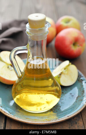 Vinaigre de Cidre en bouteille en verre et des pommes fraîches sur fond de bois Banque D'Images