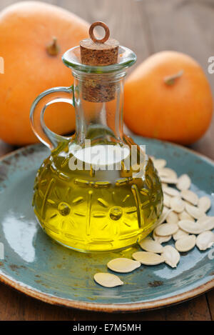 L'huile de graines de citrouille en bouteille avec des graines de citrouille et sur fond de bois Banque D'Images