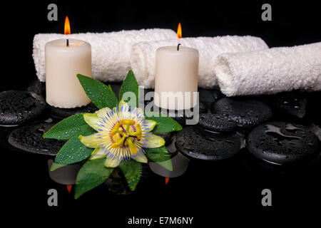 Spa still life of passiflora fleur, feuille verte avec des serviettes, et des bougies sur le zen pierres dans l'eau, réflexion libre Banque D'Images