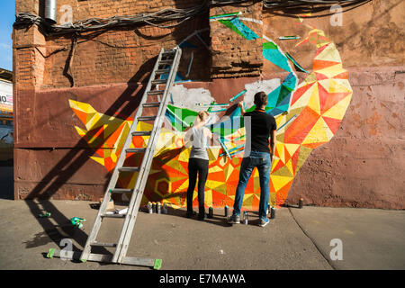 Moscou, Russie. Samedi, Septembre 20th, 2014. Street art festival 2014 Artside continue à Moscou. Les murs ternes de vieux bâtiments de l'ancienne usine de confiserie Octobre rouge se tournent vers le street art gallery. L'usine a déménagé à un autre endroit, l'ancien site industriel dans le centre historique de Moscou a été convertie en zone de loisirs et d'affaires. Le festival se poursuit. Maria et Maxime d'Siberianberries art group travaux sur le Firebird. Crédit : Alex's Pictures/Alamy Live News Banque D'Images