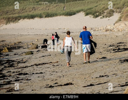 Deux vacanciers, marcher le long de la plage de Sennen Cove à Cornwall. Banque D'Images