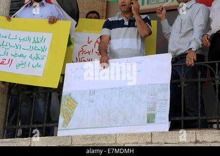 Ramallah, Cisjordanie, territoire palestinien. Sep 21, 2014. Des manifestants palestiniens tiennent des pancartes lors d'une manifestation à l'extérieur de l'Asie corporation 'une entreprise d'ingénierie' après avoir été accusés de collaborer avec les autorités israéliennes dans des projets de colonisation, dans la ville de Ramallah, en Cisjordanie sur Septemper 21, 2014. L'Administration civile israélienne en Cisjordanie est la promotion d'un plan visant à expulser des milliers de Bédouins de terres à l'Est de Jérusalem et les déplacer de force d'une nouvelle ville dans la vallée du Jourdain © Shadi Hatem/APA/Images/fil ZUMA Alamy Live News Banque D'Images