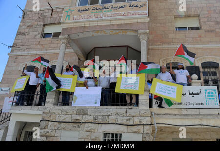 Ramallah, Cisjordanie, territoire palestinien. Sep 21, 2014. Des manifestants palestiniens tiennent des pancartes lors d'une manifestation à l'extérieur de l'Asie corporation 'une entreprise d'ingénierie' après avoir été accusés de collaborer avec les autorités israéliennes dans des projets de colonisation, dans la ville de Ramallah, en Cisjordanie sur Septemper 21, 2014. L'Administration civile israélienne en Cisjordanie est la promotion d'un plan visant à expulser des milliers de Bédouins de terres à l'Est de Jérusalem et les déplacer de force d'une nouvelle ville dans la vallée du Jourdain © Shadi Hatem/APA/Images/fil ZUMA Alamy Live News Banque D'Images