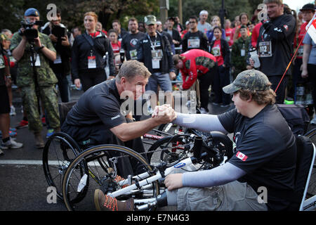 Ottawa, Canada. Sep 21, 2014. L'athlète paralympique et le Colonel honoraire Rick Hansen (L'avant) encourage la Preston à Tyler 2014 Course de l'Armée du Canada à Ottawa, Canada, le 21 septembre, 2014. Les soldats blessés et les athlètes handicapés ont été parmi les 25 000 coureurs à l'événement annuel qui aide à recueillir des fonds pour les familles des militaires. Credit : Cole Burston/Xinhua/Alamy Live News Banque D'Images