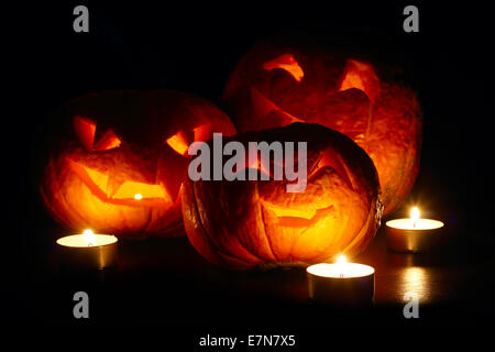 Citrouilles d'halloween cute allumé des bougies et isolé sur fond noir Banque D'Images